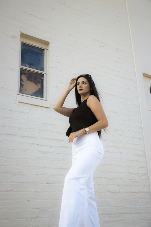 a woman wearing a black shirt standing next to a white brick wall