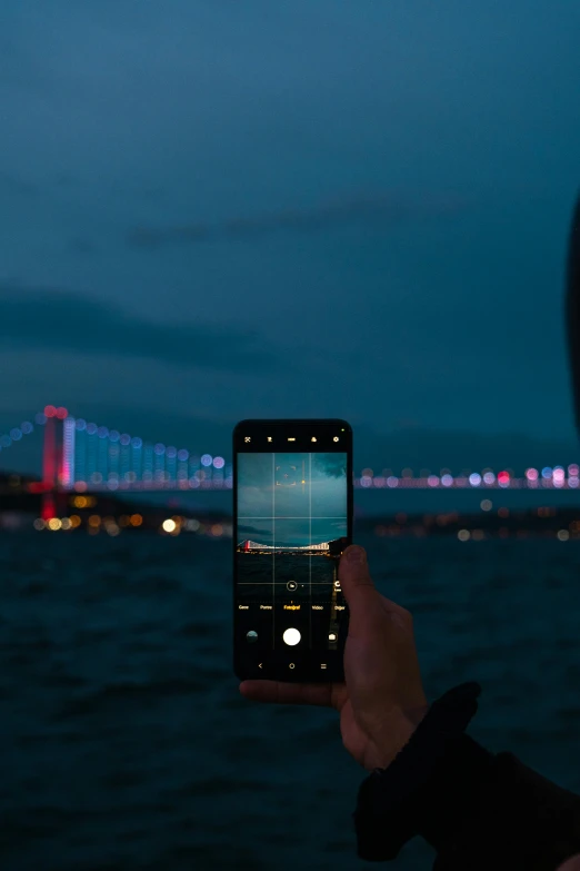 someone taking a picture of some kind of bridge in the night time