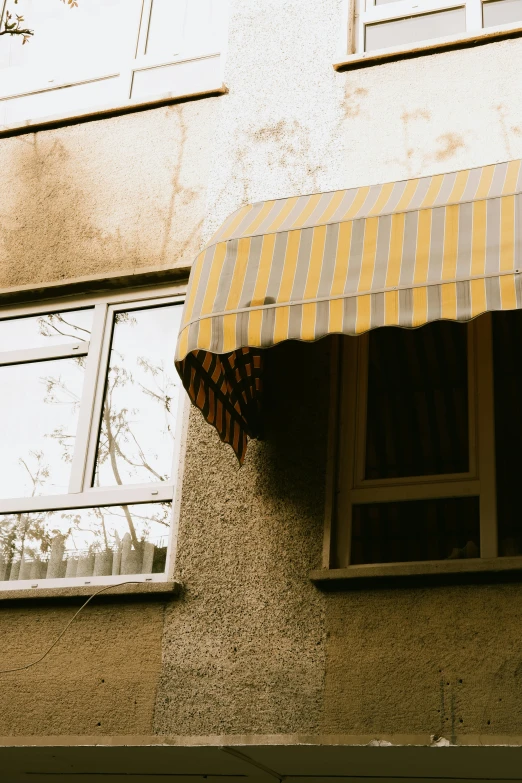 an open window sitting below a striped yellow and white awning