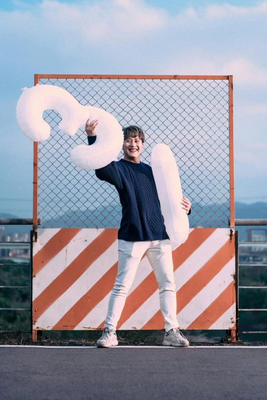 man in grey sweater holding up large white item