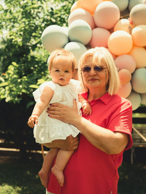 the woman is holding her little girl near balloons