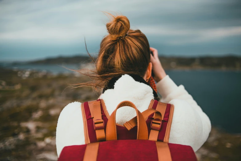 back of girl wearing a backpack overlooking the water