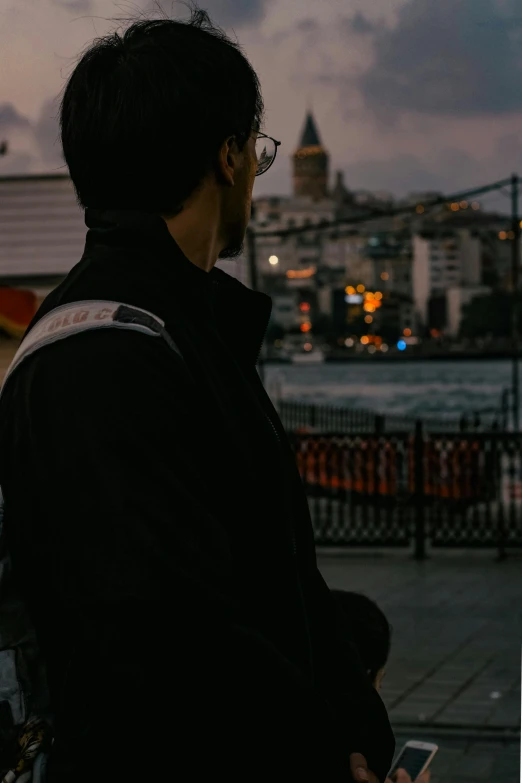 a man wearing a jacket looks out on the water