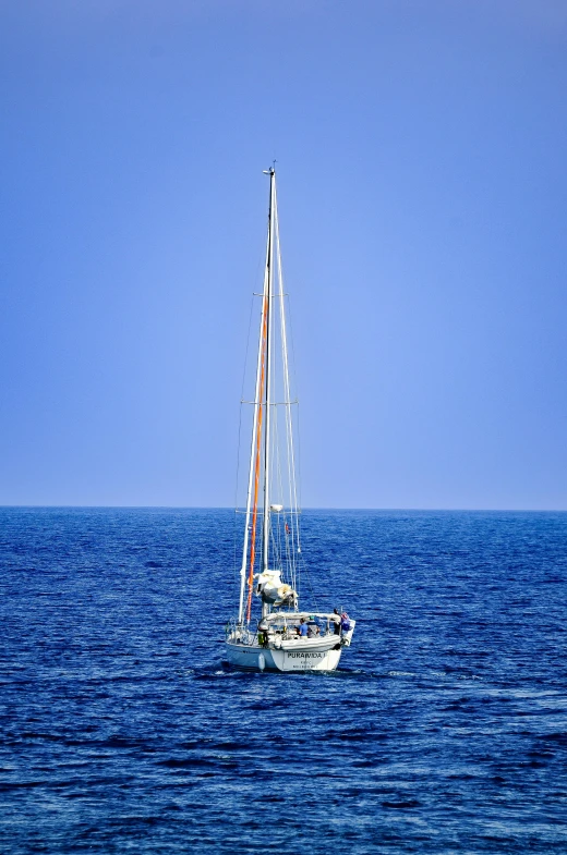a boat sailing in the blue water with a white sail