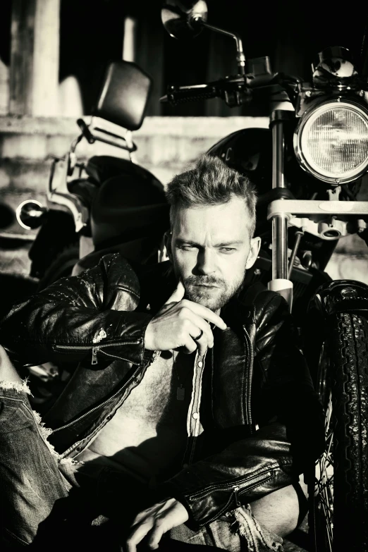 the man sitting next to a motorcycle with his hand on his knee