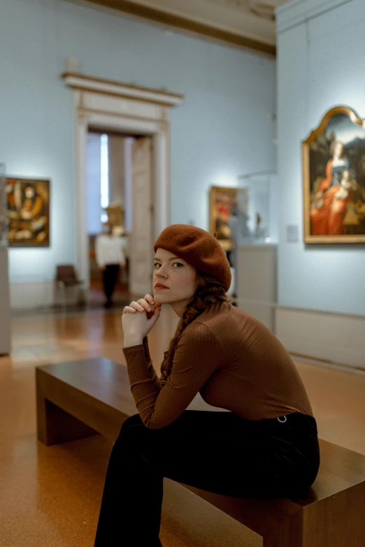 a woman is sitting on a bench in an museum