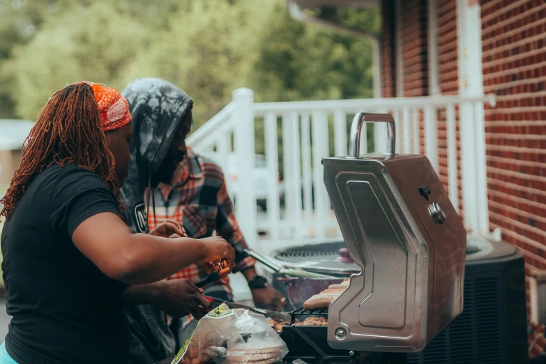 two people cooking on top of an outdoor grill