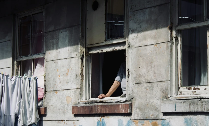 the man is looking out the window in the old building