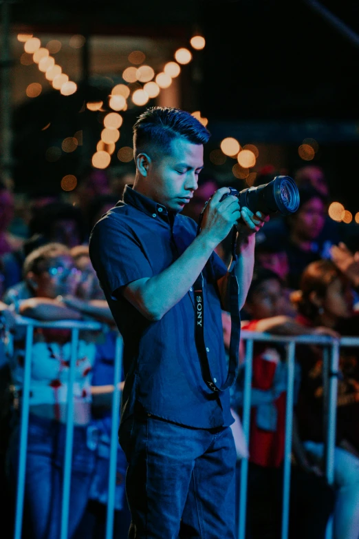 a man standing and holding up his camera in front of an audience