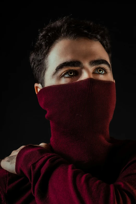 a young man wearing a burgundy shirt and neck scarf to cover his eyes