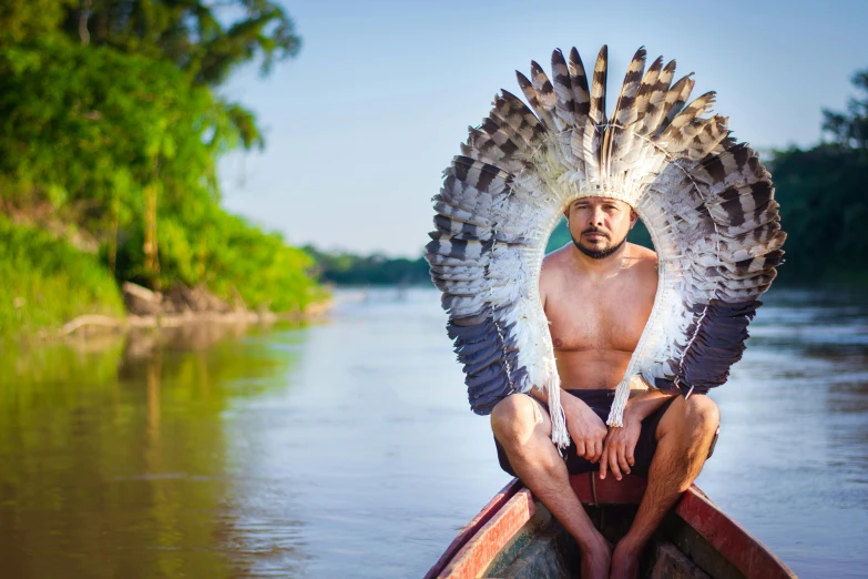 a man with an eagle headdress sitting in a canoe