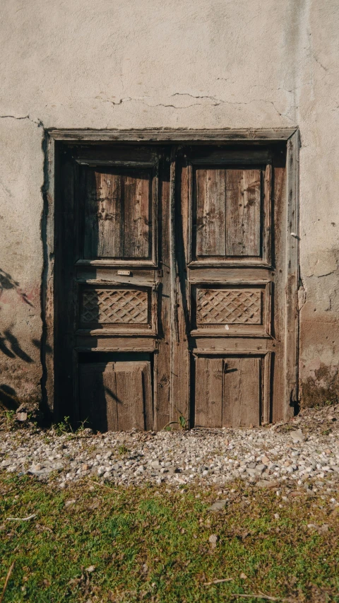 a double old wooden door sitting outside a building