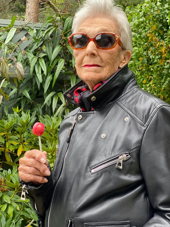 a woman wearing sunglasses holding a red flower