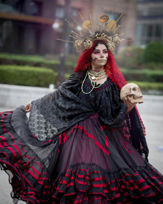 an individual dressed in costume and with a skull in her hand