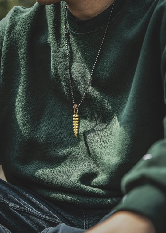 a man sits down and looks ahead with a bead on his necklace