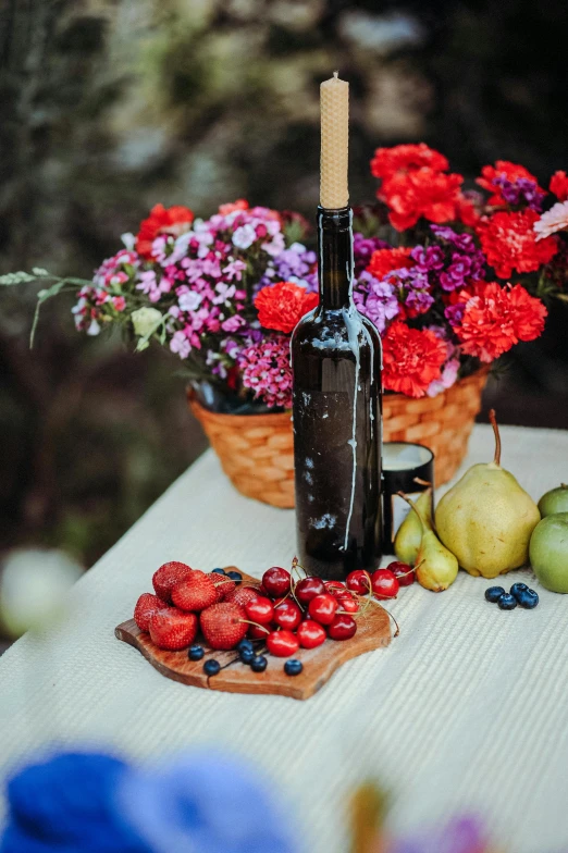 a bottle of wine sitting next to some flowers and fruit