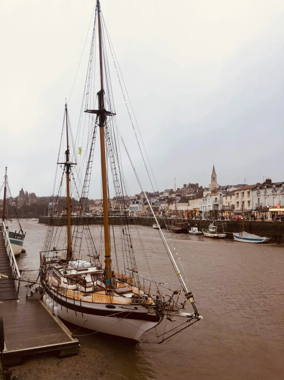 a sailboat docked on a pier with houses in the background