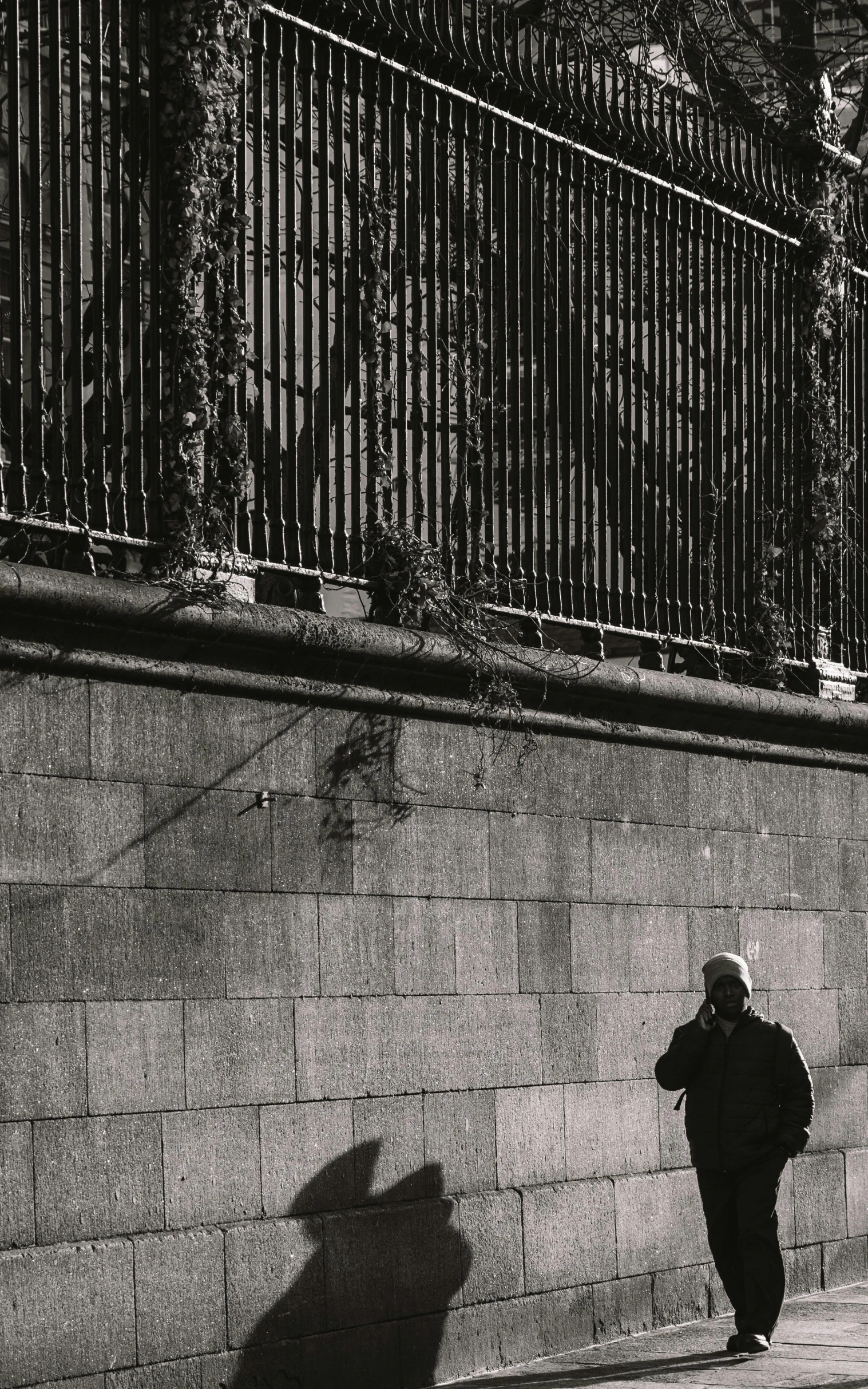 a person on a sidewalk is leaning against a fence