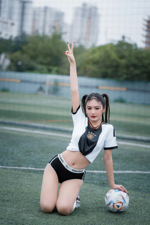 a young woman kneeling and holding a soccer ball