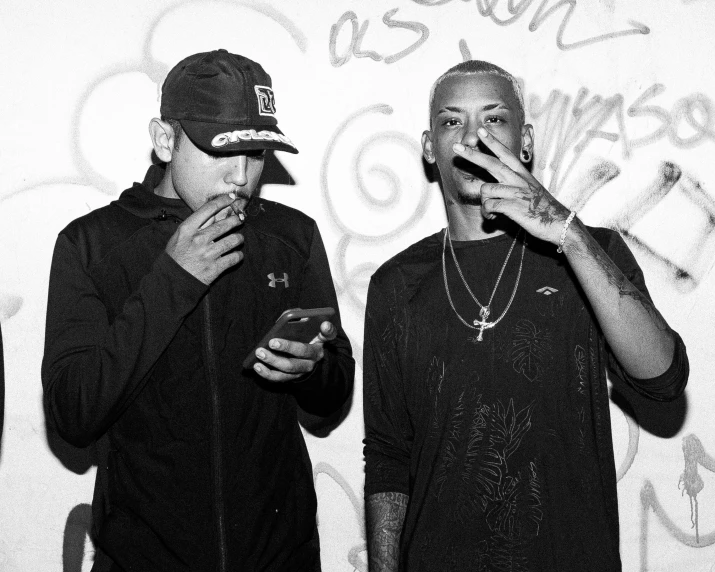 two young men smoking in front of graffiti
