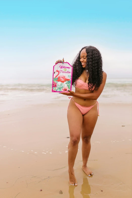 a woman in a pink bikini holding a gift box on the beach