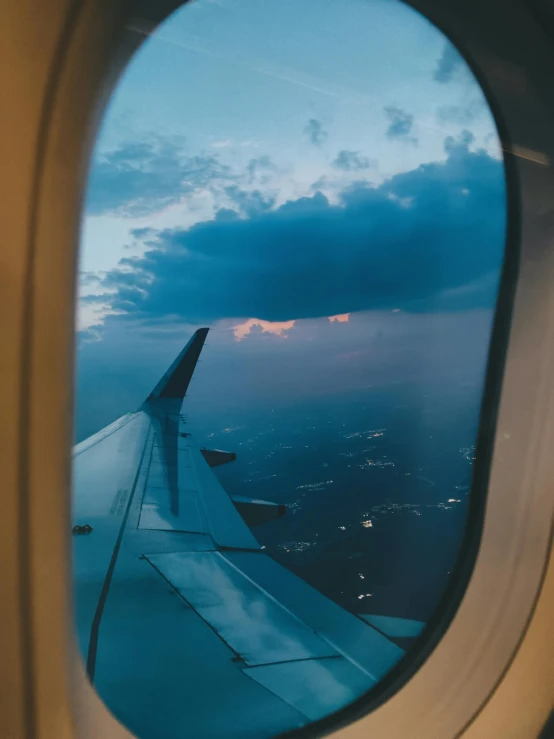 a plane window looking at the sky over land and ocean