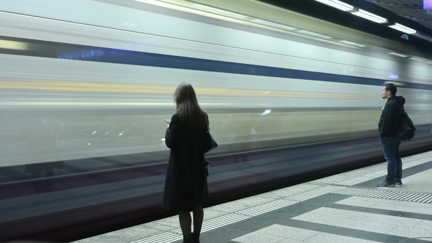 a couple of people waiting on a subway platform for a train