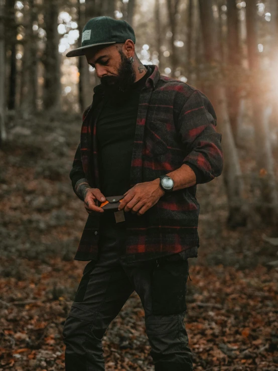 man wearing plaid jacket in woods taking pos