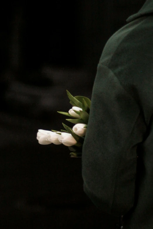 a woman in a green sweatshirt holds white flowers