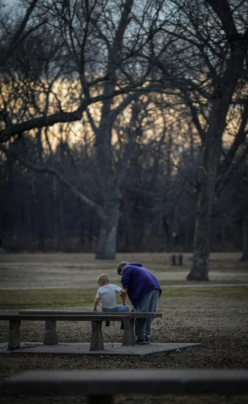 a woman and child sit on a bench in the park