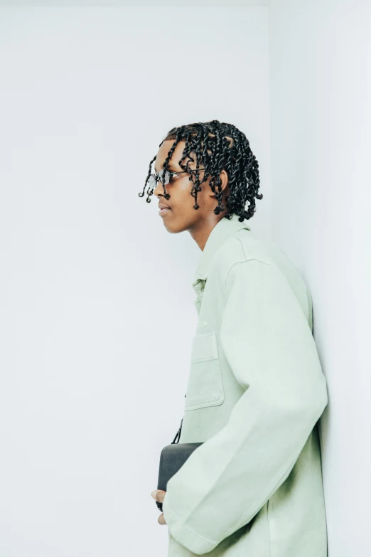 a young person stands against the wall in front of white walls