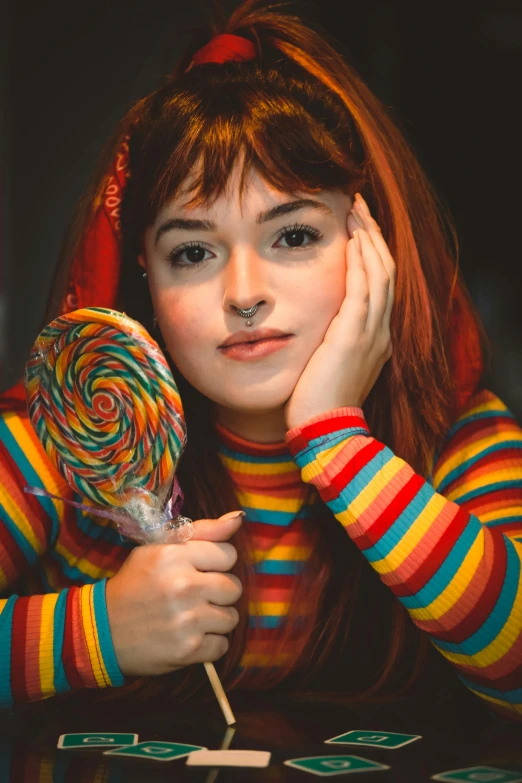 a woman with long hair sitting next to a lollipop