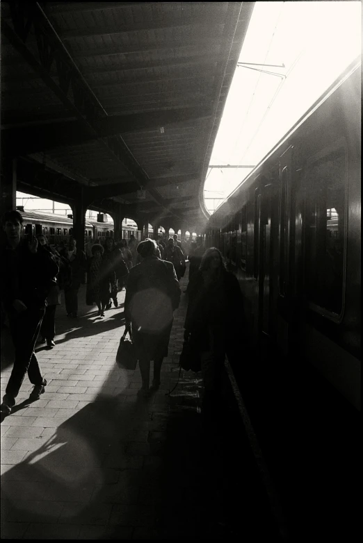 a black and white po of a person walking down the sidewalk near a train