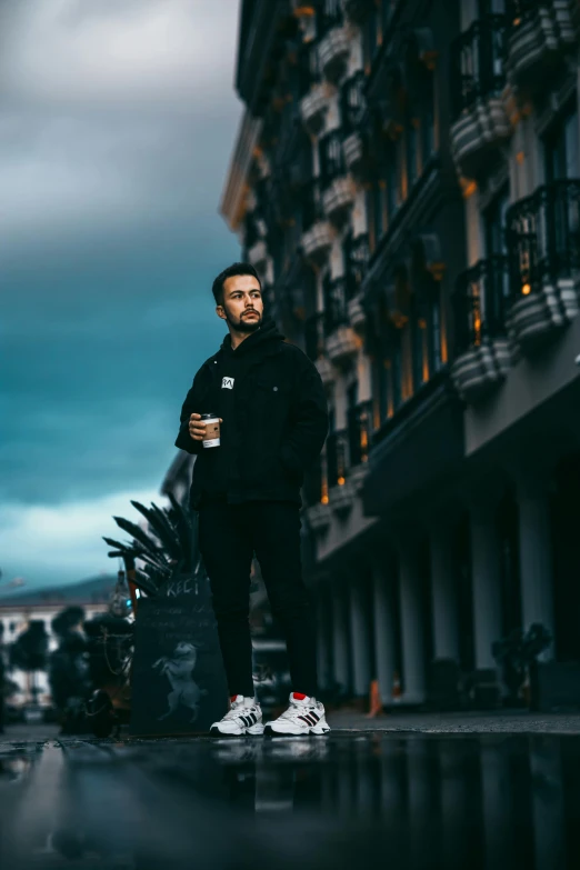 a man is standing in the rain near an apartment building