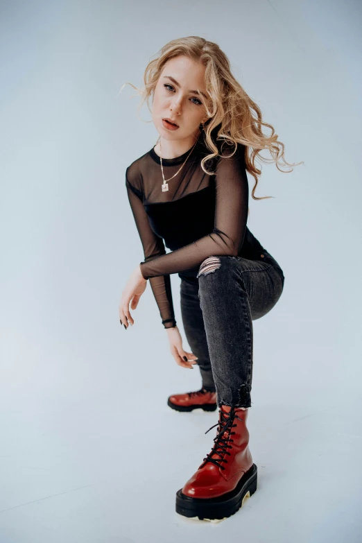 a woman in red boots standing up and leaning against the wall