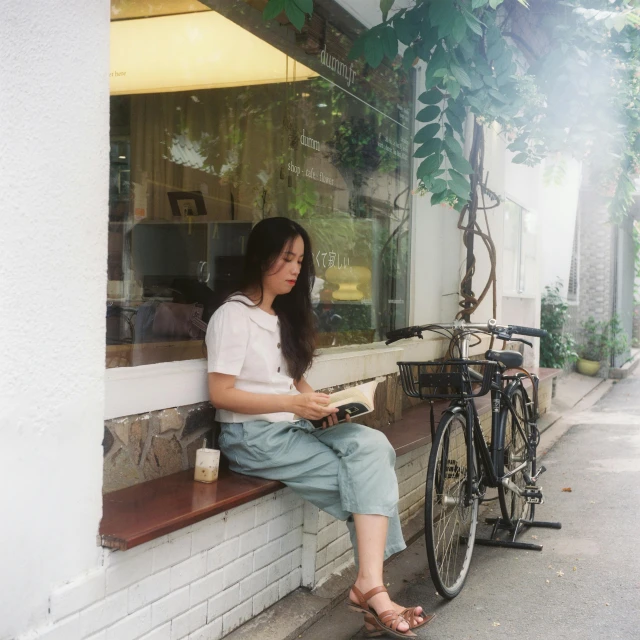 the woman is sitting on the ledge reading a newspaper