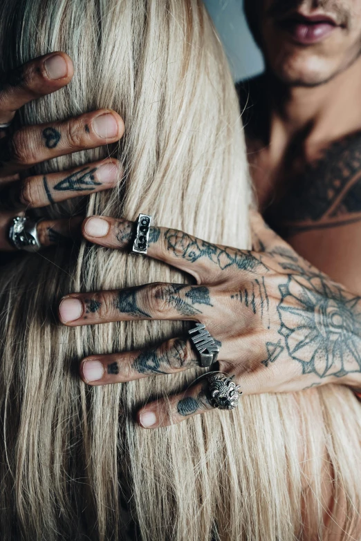 tattooed hands being worn over a blond long haired woman