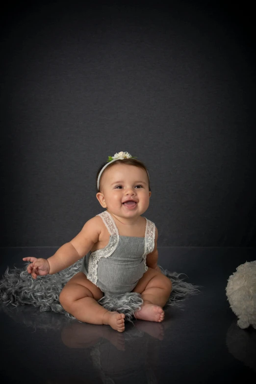 a baby in grey is sitting on a blanket