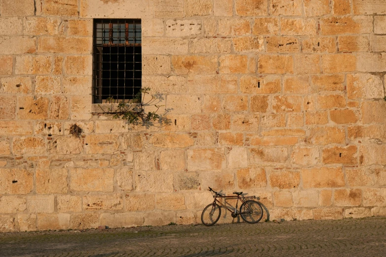 a bike parked in front of an old brick wall with a window