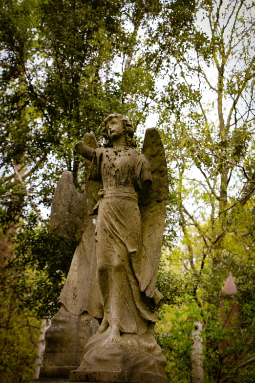 a statue stands in the woods in front of trees