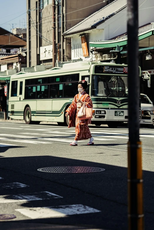 a woman in kimono walking across the street