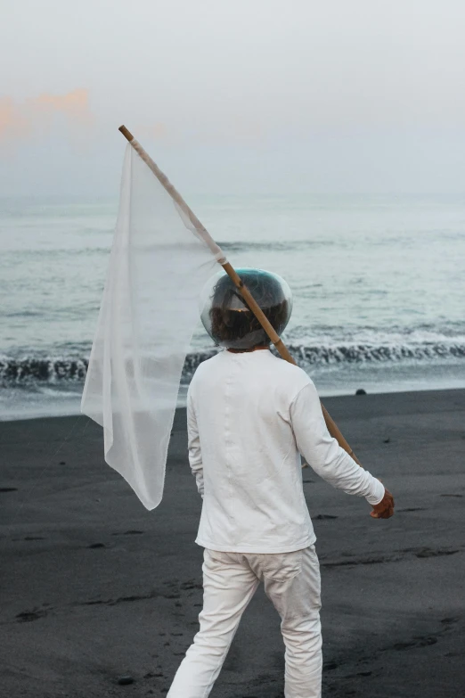 the man holds up his fishing net on the beach