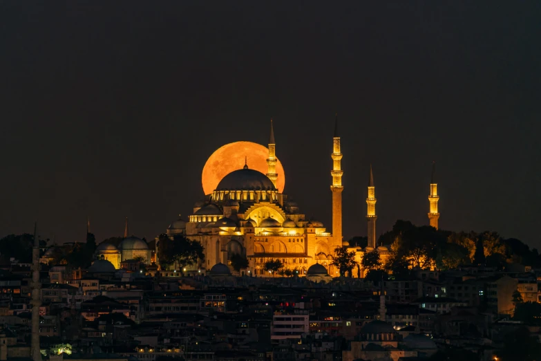 a lit up mosque and towers at night with lights on