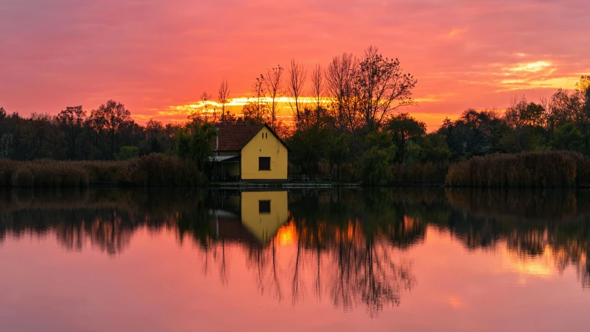 a boathouse sits out on a lake at sunset