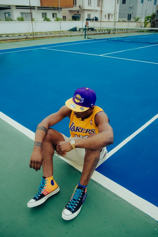 a man sits on the court wearing colorful shoes