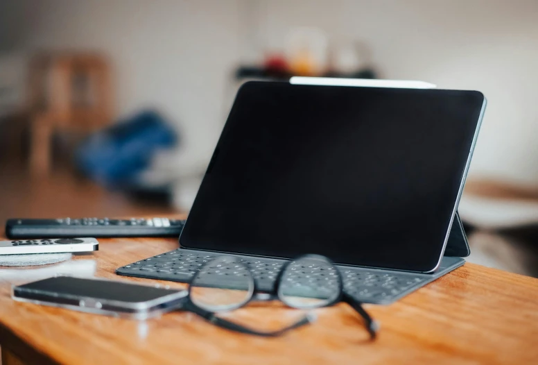 there is a laptop with glasses and a phone on top