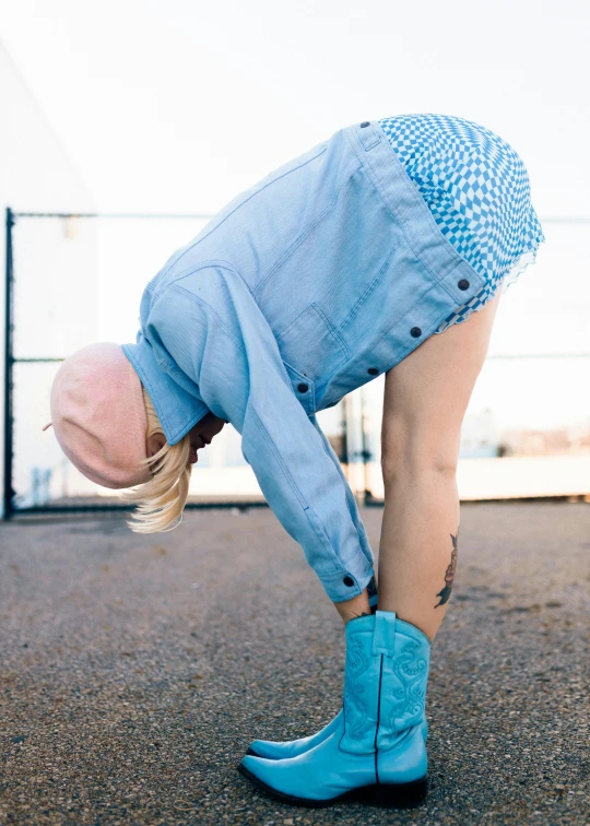 a little girl in blue boots does a handstand