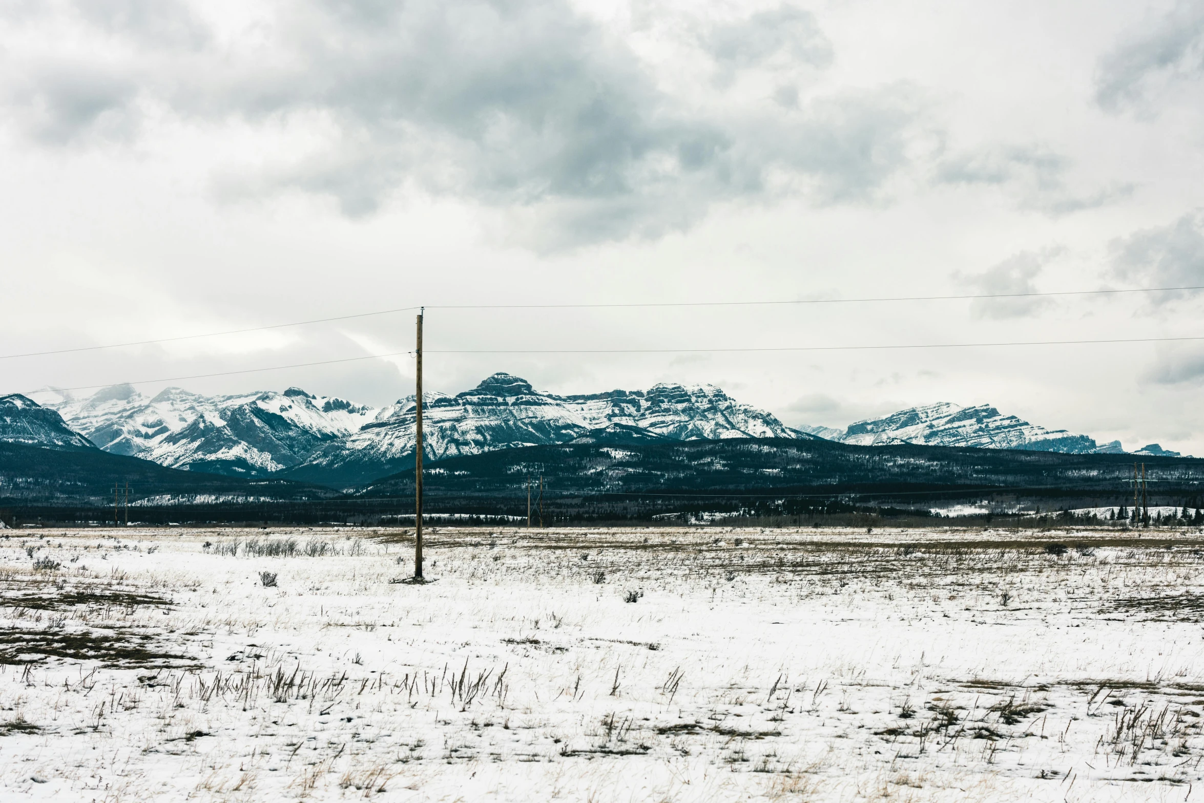 a fence sitting in the middle of a field covered with snow