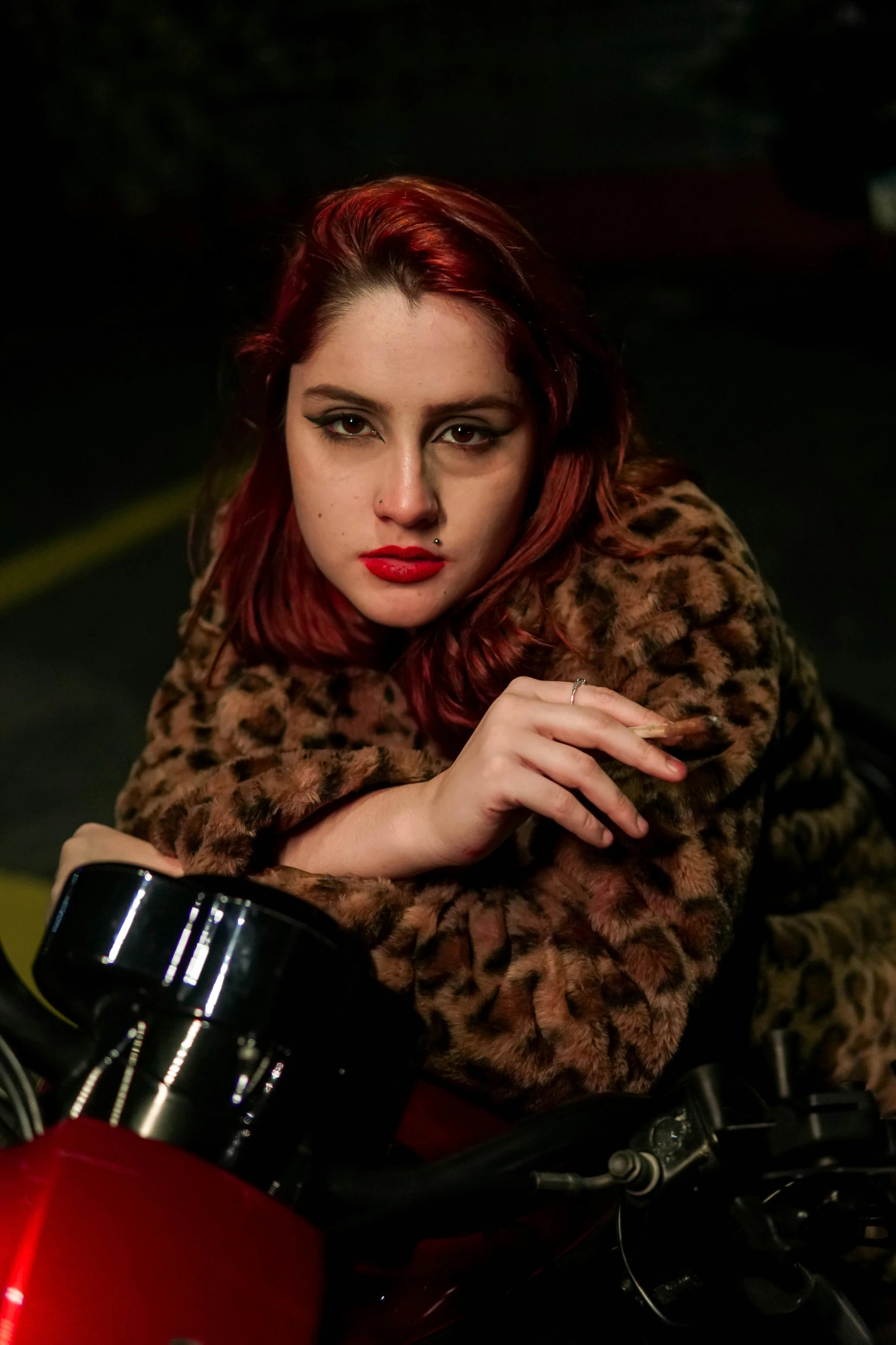 the young woman is sitting on her red motorcycle