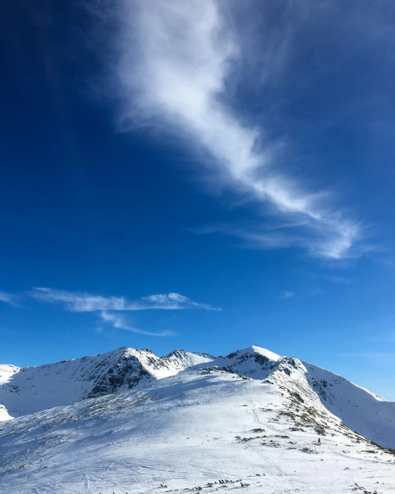 people walking up a snowy hill with skis